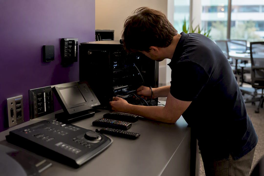 Hands adjusting AV equipment and desk booking controls