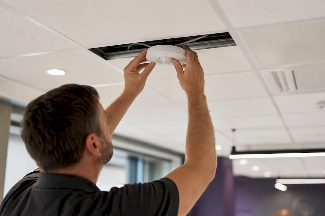 Hands installing smart occupancy sensor