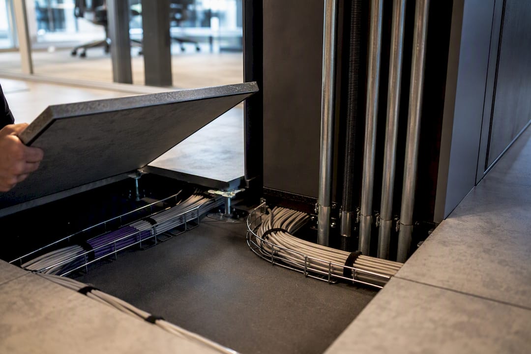 Technician inspecting organised office cable pathways