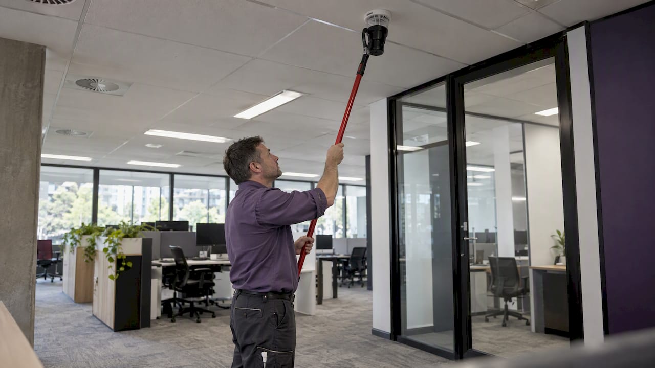 Technician testing a smoke detector in a new office